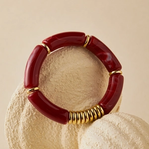 Macro detail of amber resin beaded bracelet with gold accents on marble stone