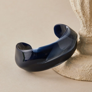 Detail of blue marble acrylic cuff bracelet with artistic wavy texture and glossy finish