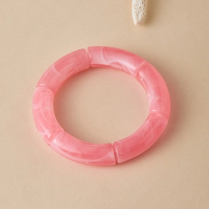 Detail van roze marmeren acryl armband op beige achtergrond met een witte schelp als decor