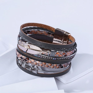 Détail du bracelet bohème en cuir multicouche avec plume en métal et cristaux