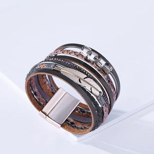 Détail d'un bracelet bohème multicouche avec lanières en cuir, plume argentée et fermoir aimanté