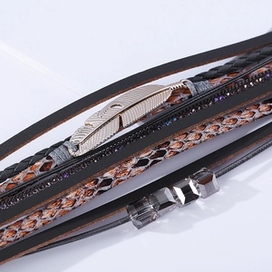 Détail d'un bracelet bohème multicouche en cuir avec plume argentée et cristaux violets