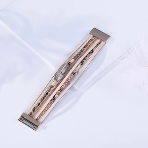 Détail d'un bracelet multicouche en cuir avec charm plume en argent et fermoir magnétique