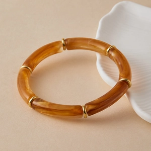 Macro detail of Bohemian resin tube bracelet with amber texture and gold rings