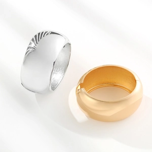 Polished gold and silver wide drum spring bangles with a minimalist mirror finish