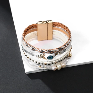 Detalle de pulsera de cuero multicapa con perla de ojo de la suerte y cierre imán