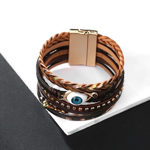 Detalle de pulsera multicapa de cuero bohemio con ojo turco y cierre magnético dorado