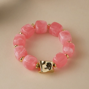 Detail view of pink marble texture resin beads and golden metallic accents on a bracelet