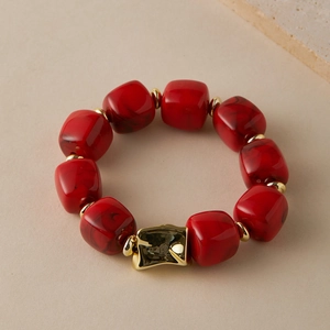 Detail of red marble texture acrylic beads with gold spacers and irregular metal clasp