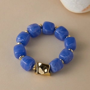 Detail of blue acrylic beads and gold geometric accents on an irregular chunky bracelet