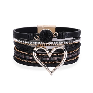 Detail van een boheemse meerlaagse zwarte lederen armband met hartvormige hanger en magneetsluiting