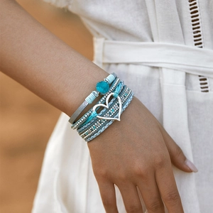 Detail van een bohemian meerlaagse armband met blauwe stenen en hartjesbedeltje