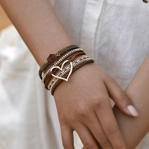 Detail van een boho meerlaagse leren armband met gouden hart en glanzende kristallen