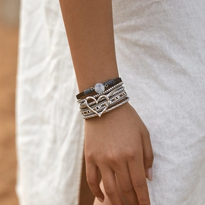 Detail van een bohemian meerlagige armband met zilveren hartje en gevlochten textuur