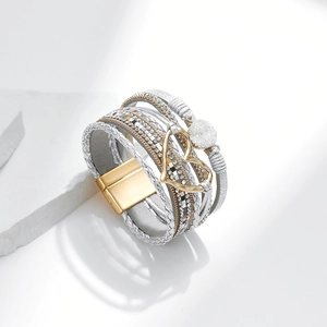 Detail eines mehrlagigen Boho-Armbands mit silbernem Leder, Strass und Herzanhänger