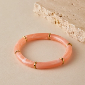Detail of coral pink resin tube beads and gold spacers on a stretch bracelet