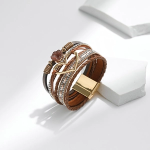 Detail eines mehrlagigen Boho-Armbands mit goldenem Herzanhänger und Magnetverschluss