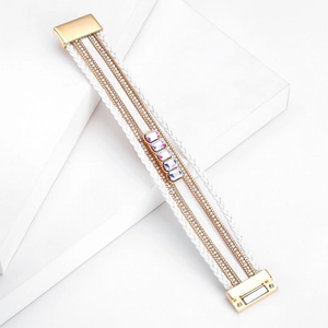Dettaglio di un bracciale multistrato in pelle bianca con cristalli e chiusura magnetica dorata
