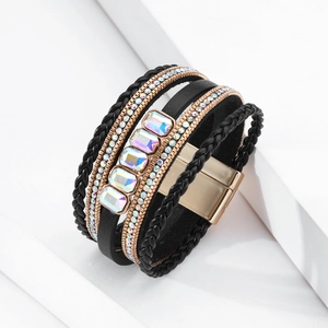 Dettaglio di un bracciale boho multistrato con pelle nera, strass e chiusura magnetica d'oro