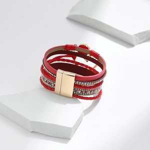 Detail eines roten mehrlagigen Lederarmbands mit Strasssteinen und goldenem Magnetverschluss