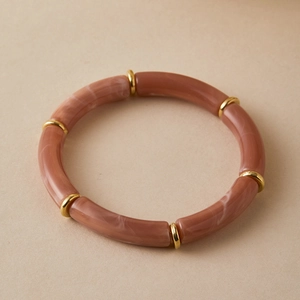 Detailed macro view of marble textured resin tube beads and golden spacers on a boho bracelet