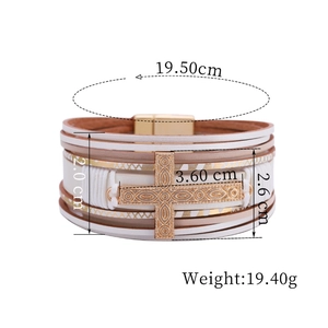 Close-up of multilayer leather bracelet with golden engraved cross and magnetic clasp