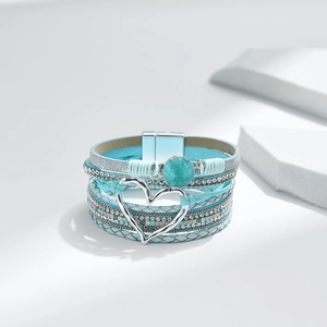 Detail eines mehrlagigen Boho-Armbands mit blauem Leder, Strasskette und Herzverschluss