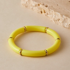 Detail of yellow tubular stretch bracelet with golden metal spacers and resin sections