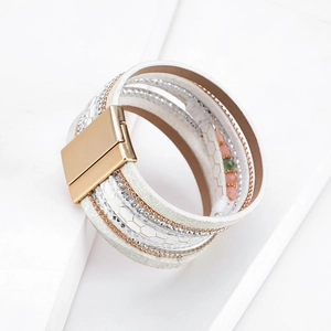 Dettaglio del bracciale boho multistrato con pelle bianca, strass e chiusura magnetica d'oro