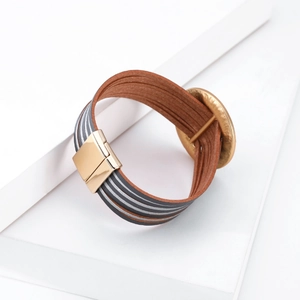 Dettaglio di bracciale bohémien multistrato in pelle con texture crine e chiusura magnetica