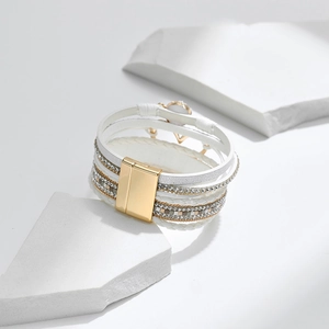 Detail eines mehrlagigen weißen Lederarmbands mit Kristall-Strasssteinen und Magnetverschluss