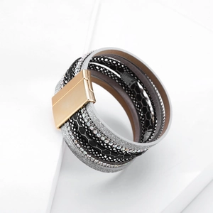Dettaglio bracciale bohémien multistrato con strass, glitter e chiusura magnetica dorata