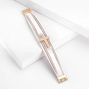 Close-up of multilayer white leather bracelet with engraved rose gold cross and magnetic clasp