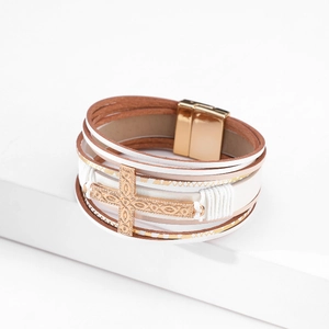 Detail of bohemian multilayer leather bracelet featuring an embossed gold metal cross