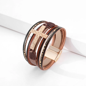 Macro view of multi-layer leather bracelet featuring an embossed golden cross and magnetic clasp