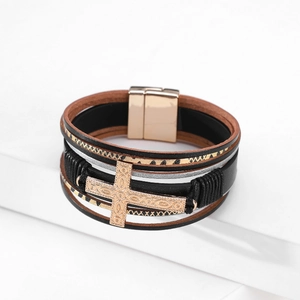 Detail of multilayer leather bracelet with rose gold cross pendant and magnetic buckle