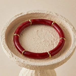 Close-up of bohemian red resin tube bracelet with golden spacers on a stone base