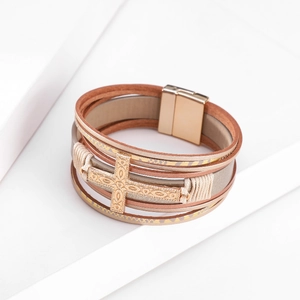 Detailed view of multilayer leather bracelet with carved gold cross and magnetic clasp