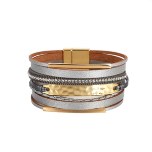 Détail d'un bracelet multicouche en cuir avec tubes dorés, strass et fermoir aimanté