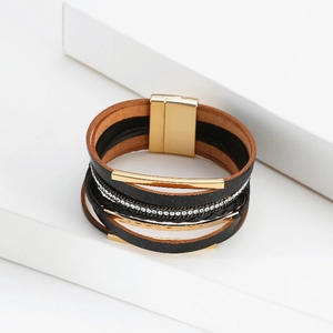 Détail du bracelet multicouche en cuir bohème avec tubes dorés et strass blancs brillants