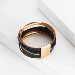 Détail d'un bracelet multicouche en cuir avec tubes dorés et fermoir magnétique
