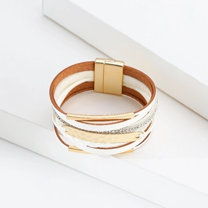 Détail du bracelet bohème multicouche en cuir avec tubes dorés et strass brillants