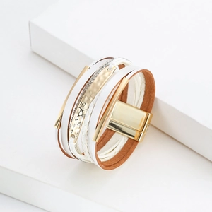 Détail d'un bracelet multicouche en cuir bohème avec fermoir magnétique doré sur support blanc