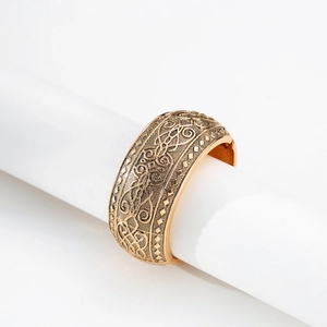 Dettaglio del bracciale rigido dorato bohémien con incisioni floreali in stile vintage
