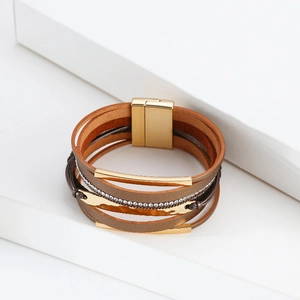 Détail d'un bracelet multicouche en cuir bohème avec tubes dorés et fermoir magnétique strass