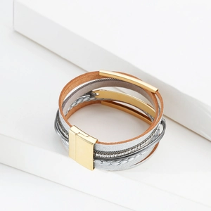 Détail du bracelet multicouche en cuir avec tubes dorés et fermoir magnétique