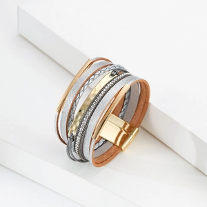 Détail macro d'un bracelet multicouche en cuir avec barres métalliques et fermoir magnétique