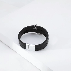Detail of double-layer black leather bracelet with silver X-shaped ornament and magnetic clasp