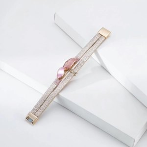 Detail of champagne leather bracelet with pink enamel leaf and sparkling X charm