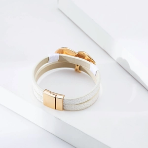 Close-up of a double-layer white leather bracelet with gold heart and magnetic clasp